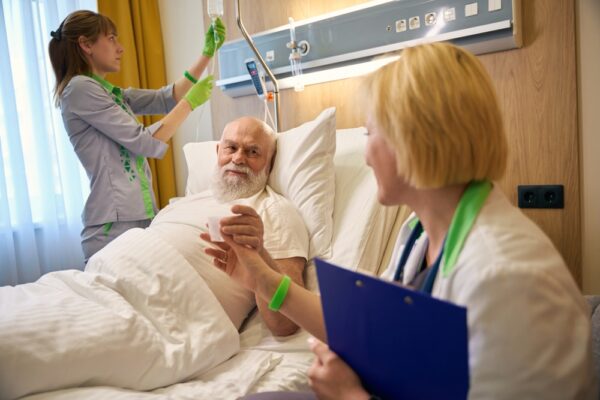 Doctor Sitting Next To Old Bearded Patient