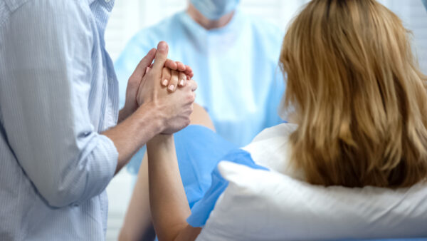Close-up Of Man Holding Wife Hand For Support During Childbirth