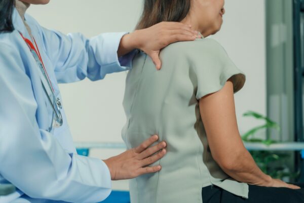 Female Doctor Examining Mature Woman With Back Pain In Clinic