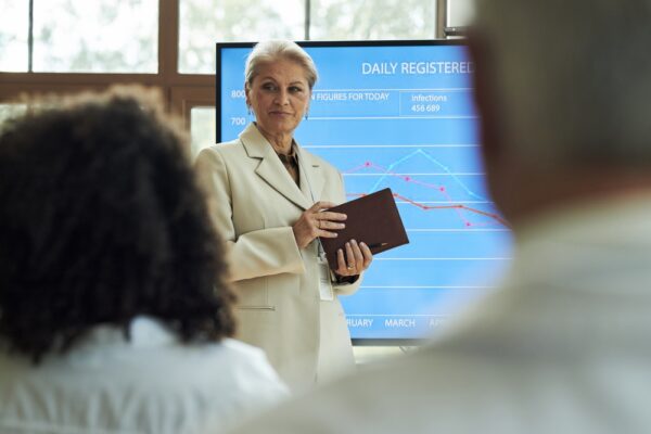Hospital Executive Presenting Medical Statistics On Large Screen